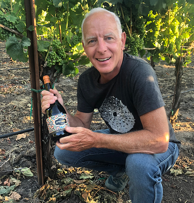 Jonathan Pey in vineyard with bottle of Spicerack Syrah